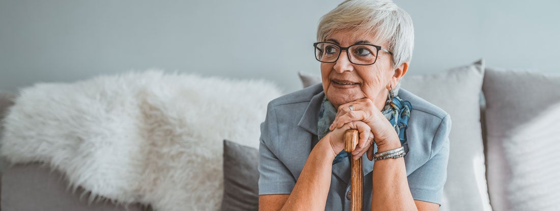 Senior gray hair women supporting on a walking cane at home. Long term care insurance benefits period.