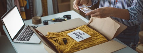 Small business owner packing product in boxes, preparing it for delivery.