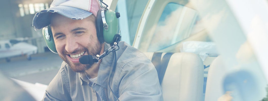 Young pilot sitting in cockpit and enjoying his job. Find Aviation Liability Insurance.