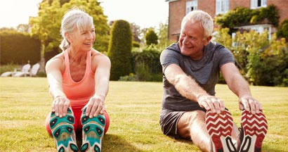 Fit mature couple stretching on the grass. Find Permanent Life Insurance.