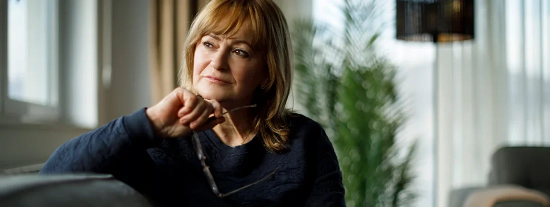 Woman sitting on sofa at home. Find Medicare Part C Supplements. 