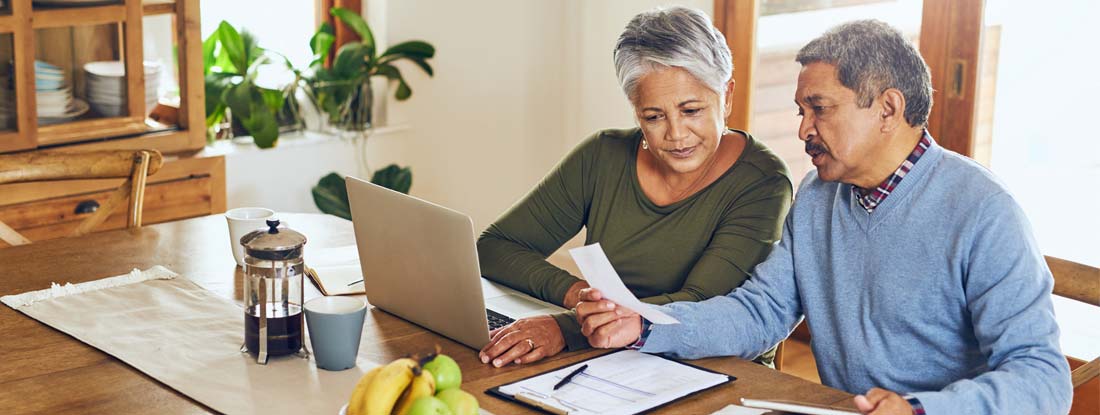 Senior couple using a laptop together at home. Long term care insurance benefits.