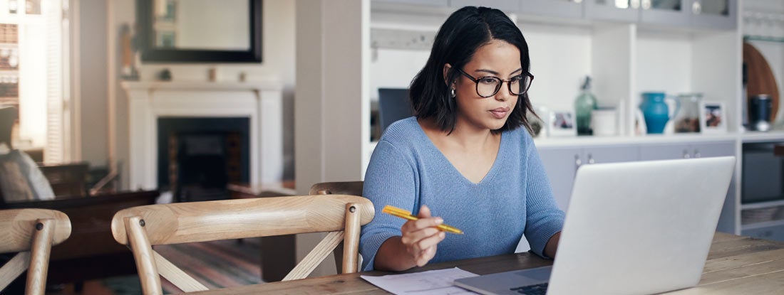 Young woman using a laptop while working from home. Car Insurance Declarations Page.
