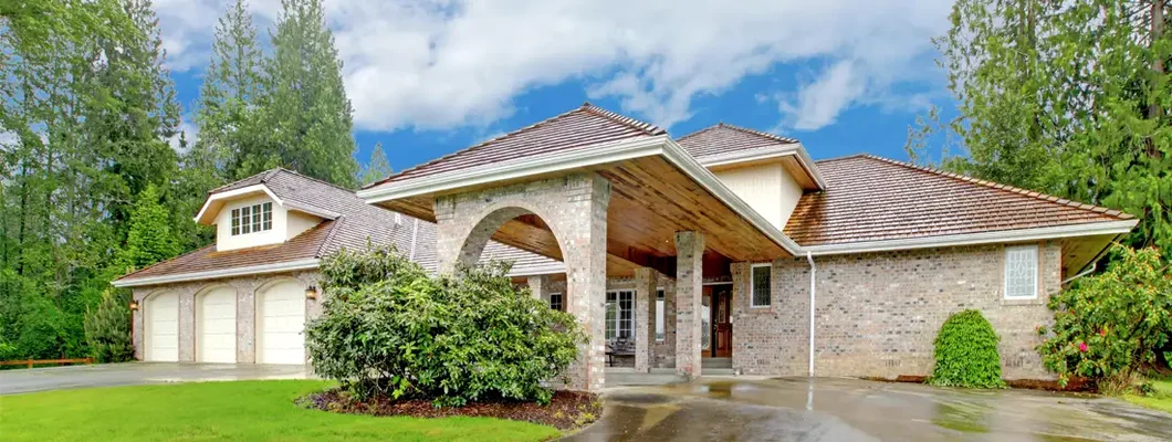 Beautiful curb appeal after rain. Large brick house with three garage spaces and driveway with arch. How to Find the Best Homeowners Insurance in Potomac, MD