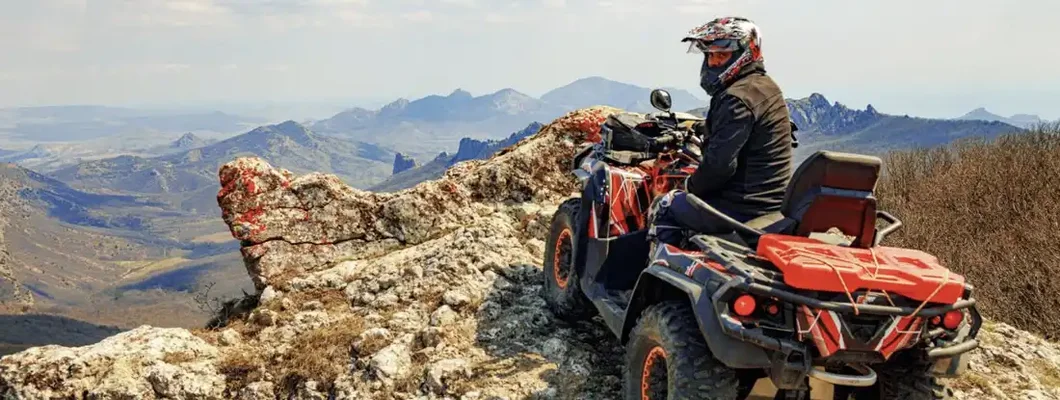 Man in helmet sitting on ATV quad bike in mountains. How Much Does ATV Insurance Cost?
