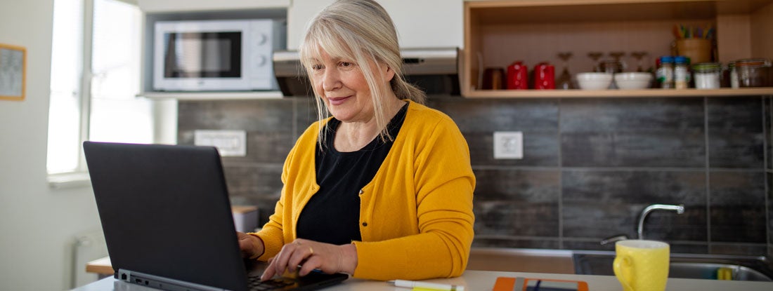 Woman using a laptop in a kitchen setting. Present value of annuity.