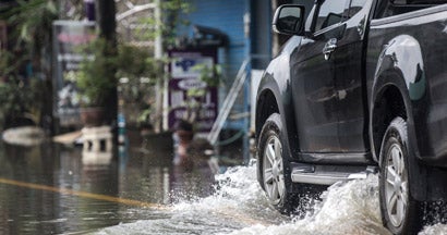 Black pickup truck driven through a flooded road. Does Car Insurance Cover Flood Damage?