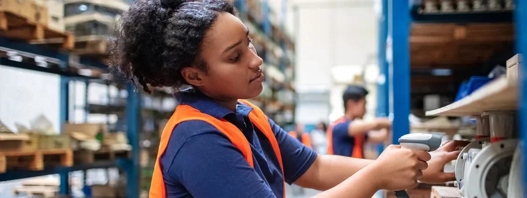 Warehouse worker checking cargo on shelves with scanner. Workers Compensation vs. General Liability Insurance.
