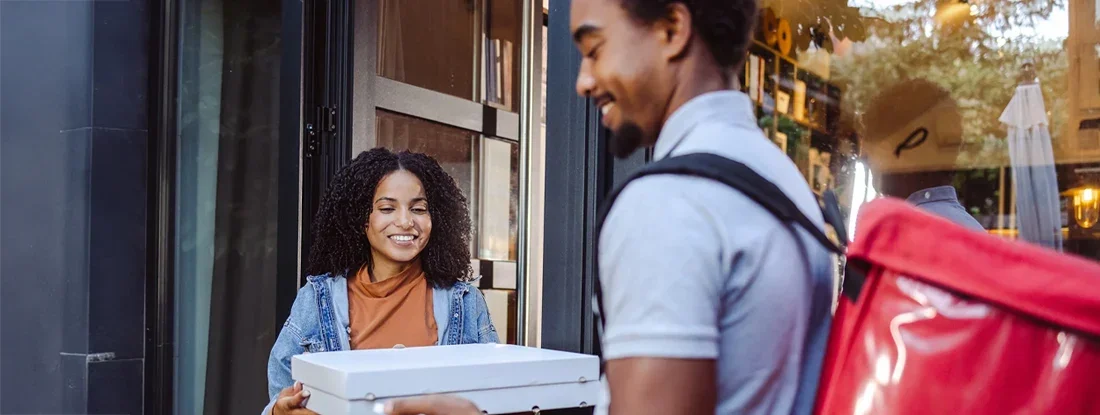 Pizza delivery man giving pizza to a woman. Find Pizza Delivery Insurance.