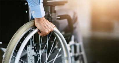 Unrecognizable man sitting in a wheelchair. Disability insurance and taxes.