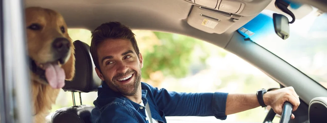 Young man taking a drive with his dog in the backseat. How to Find the Best Car Insurance in Auburn, Maine.