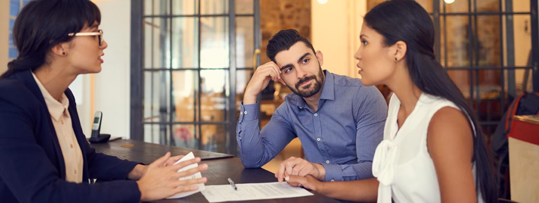Couple meeting with a financial planner in an office. Find Trustee Insurance.