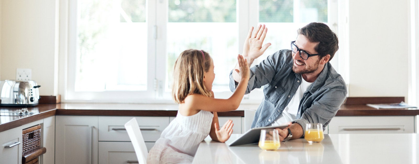 Little girl using a digital tablet with her father at home. 