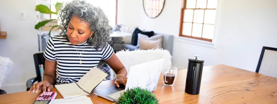 Mature Woman Working at Home on laptop. Get Coppell, Texas Business Insurance. 