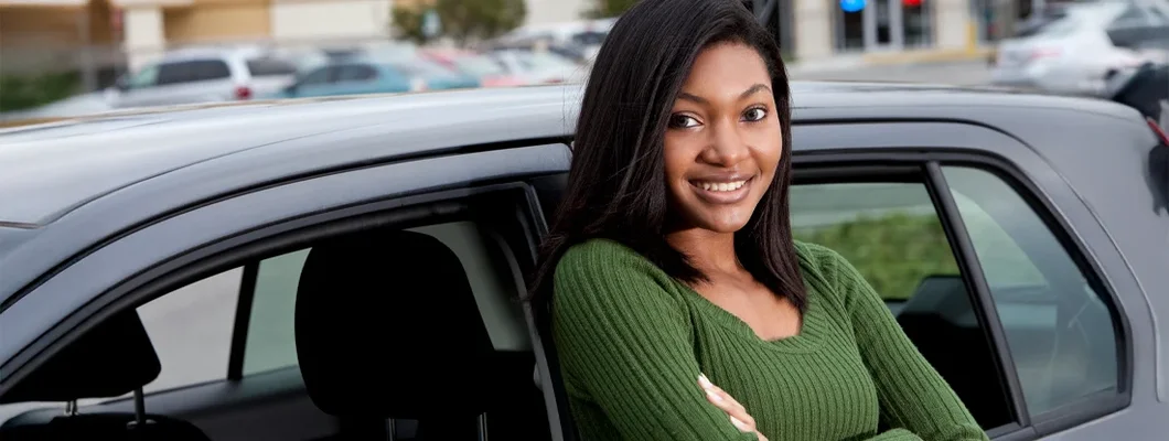 Teenage girl leaning on car. 8 Safest Cars for Teens in 2025. 