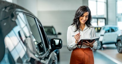 Smiling saleswoman working at a car dealership. What Is an Auto Broker? 