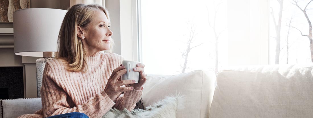 Woman relaxing on the sofa at home with a cup of coffee. Variable annuities investment. 