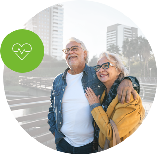 Mature couple walking arm in arm, smiling at sunset in a park.