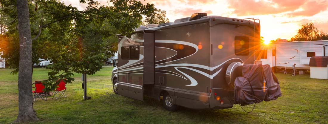 Class A recreational vehicle (RV) parked at a campsite during sunset.  Find Alabama RV Insurance.