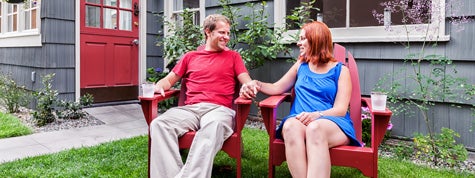 young couple in backyard discussing renting or buying home