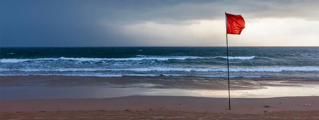 Storm warning flags on beach. Hurricane preparation guide.