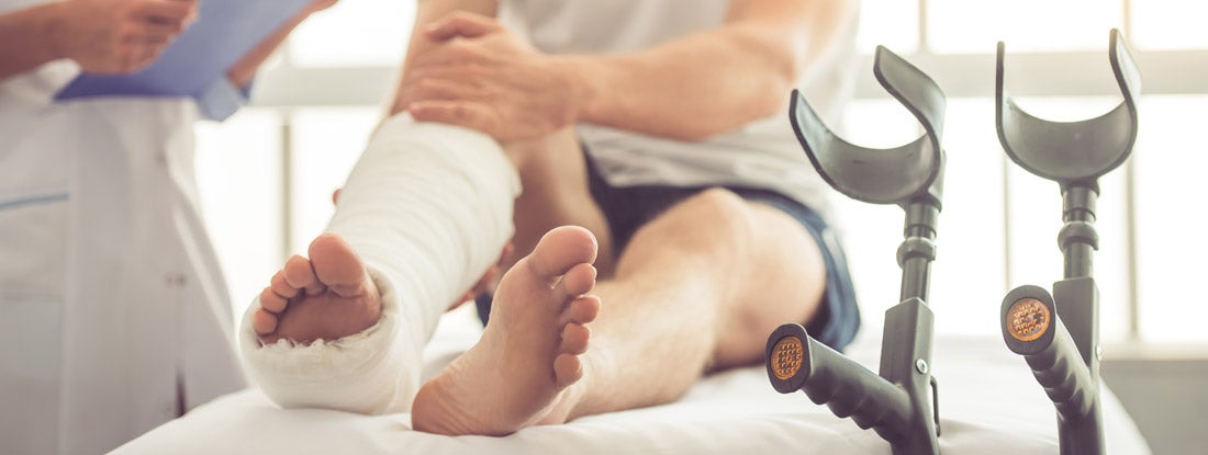 Medical doctor listening to patient with broken leg. Short term disability insurance.