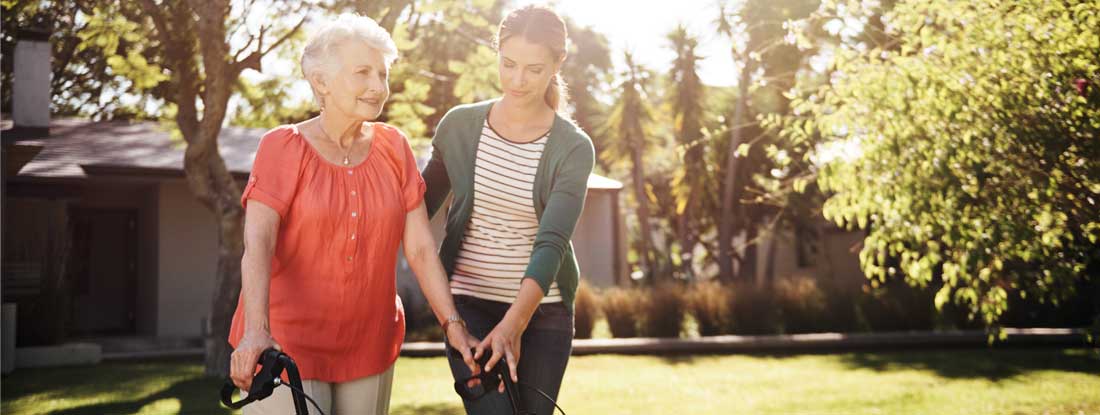 Elderly woman walking with nursing home aide. Paying for long term care without insurance.