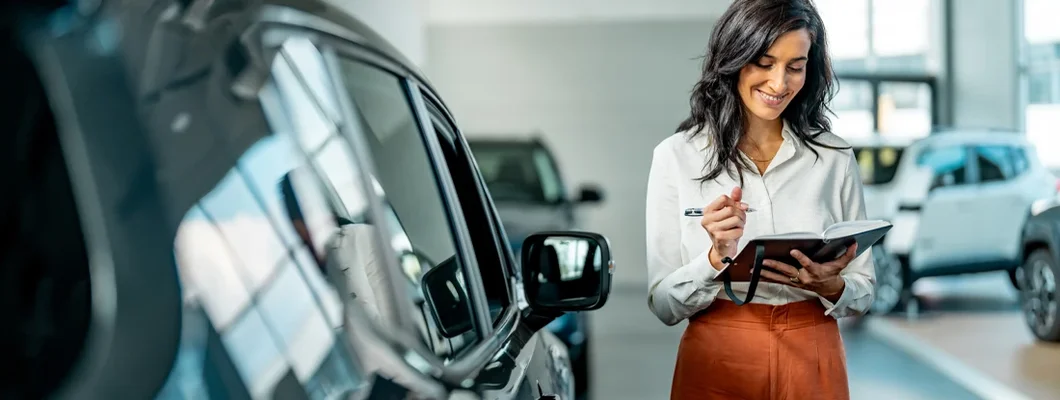 Smiling saleswoman working at a car dealership. What Is an Auto Broker? 