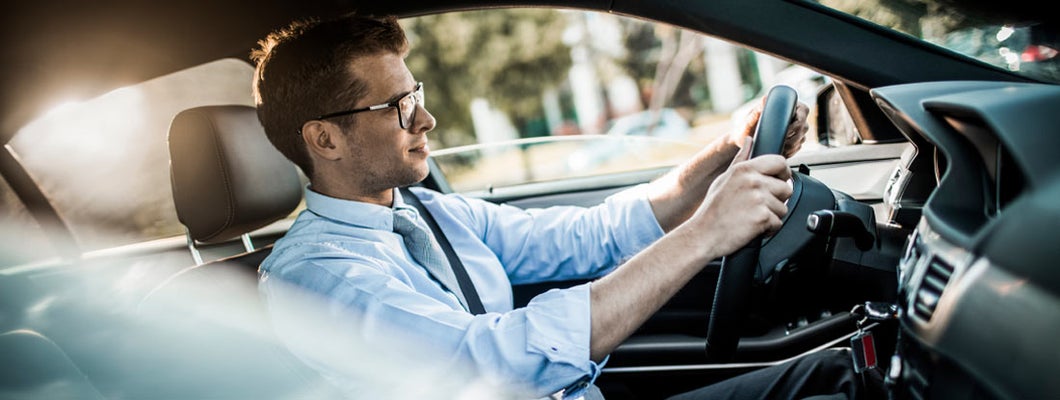 Close up photo of a businessman driving a car in city. Find Mobile Alabama car insurance.