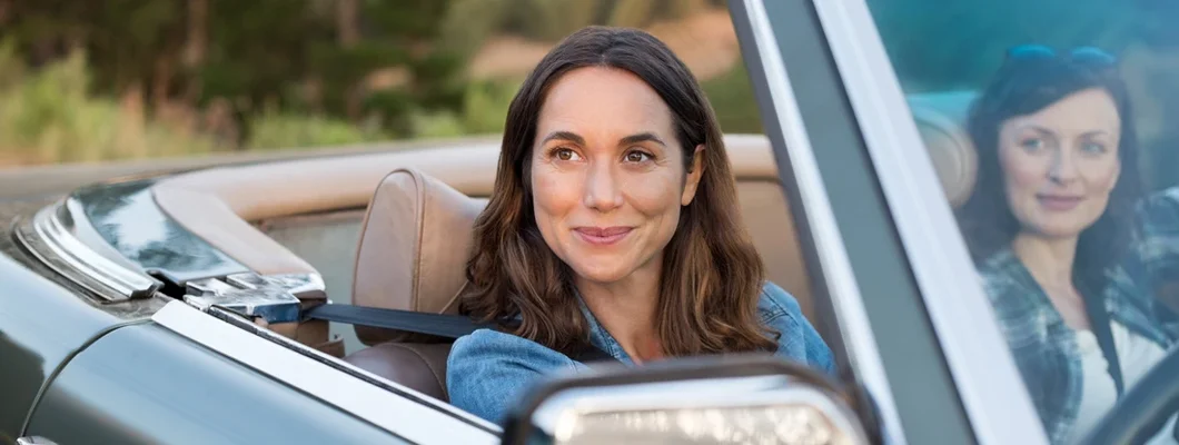 Women friends enjoying road trip in convertible car at sunset. Car Insurance in Leesburg, Virginia.