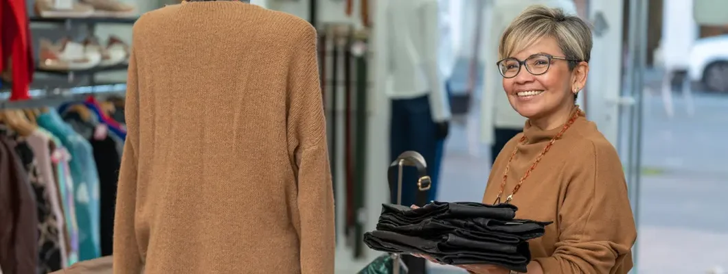 Woman store clerk working in boutique clothing shop. Find Irvine, California business insurance.