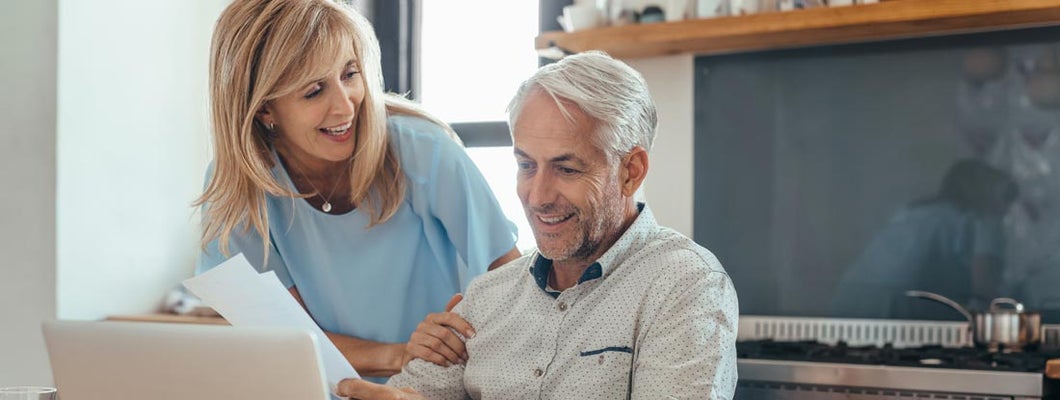 Mature couple smiling while calculating annuity interest rates together. Annuity Interest Rates.