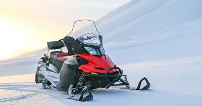 Red snowmobile on a background of snowy mountains. Customizing Your Snowmobile.