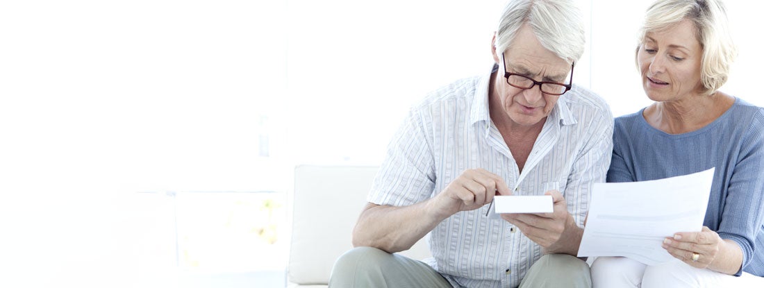 Senior couple using calculator for doing home finances. Life annuity with period certain.