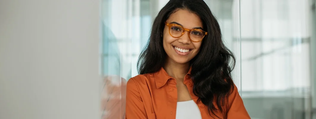 Woman wearing stylish eyeglasses looking at camera standing in modern office. Business Insurance in Leesburg, Virginia.