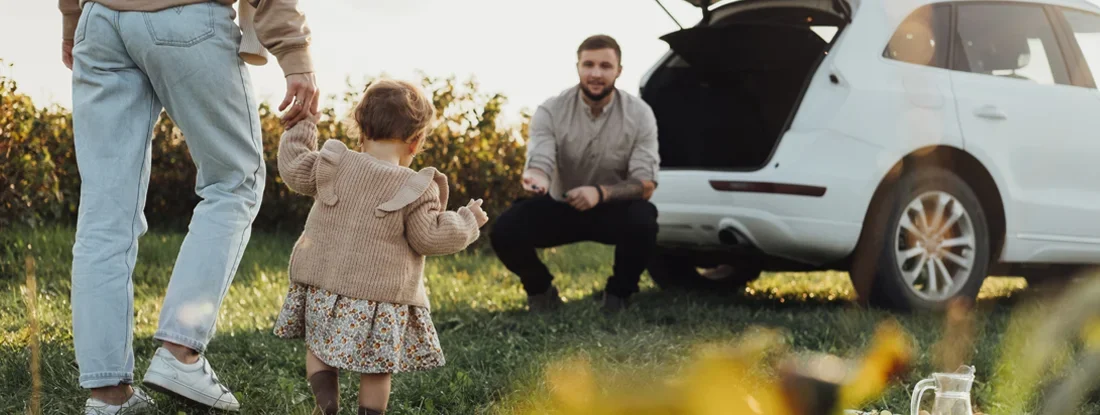 Young Family Enjoying Road Trip with SUV in background. Find SUV Insurance.