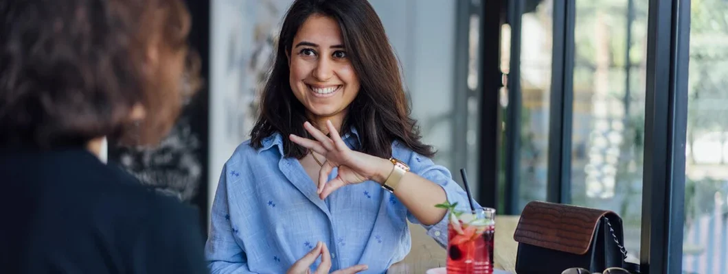 Two young woman speak in sign language. Find Interpreter Insurance.