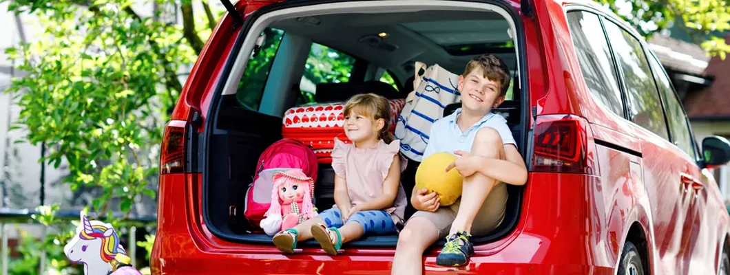 Kids sitting in car trunk before leaving for summer vacation with parents. How to Find the Best Car Insurance in Madison, Mississippi.