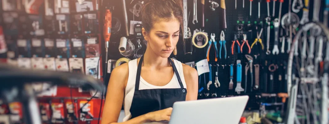 Female bicycle mechanic using a laptop. Brookline, New Hampshire Business Insurance.