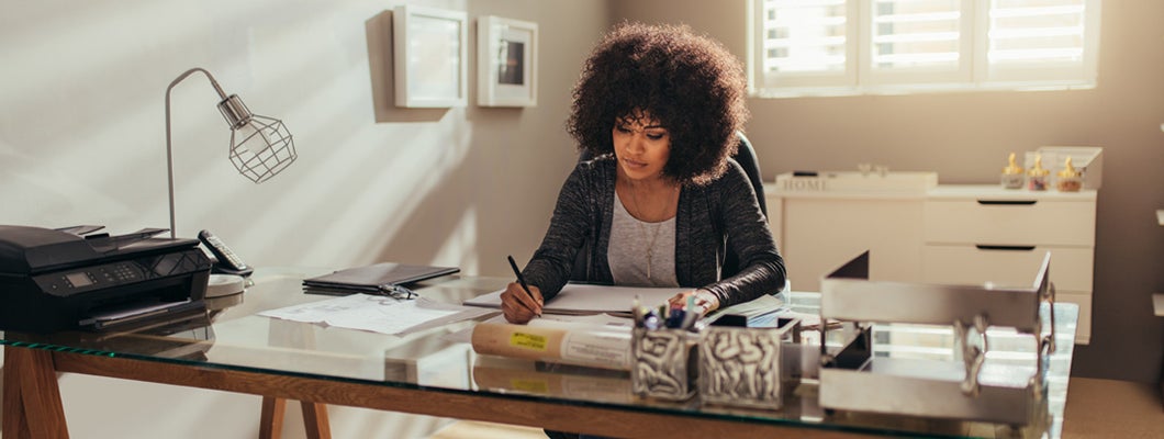 Female interior designer in home office writing business plan