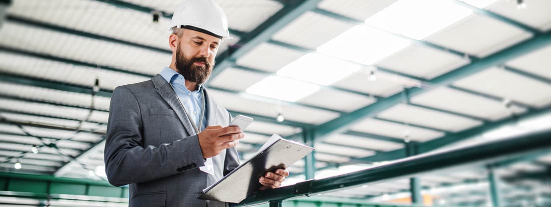 Industrial man engineer with smartphone in a factory. How to file for workers' compensation.