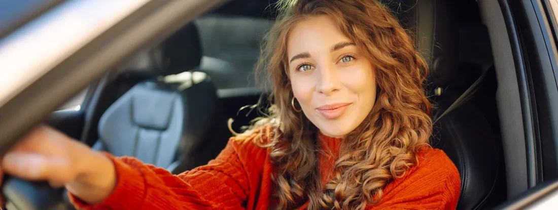 Smiling woman driving car. What's the Difference between Bodily Injury and Property Damage Auto Coverage?