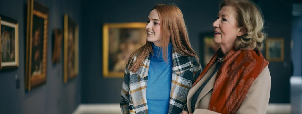Grandmother and granddaughter are looking at the paintings in the art gallery. Find Art Gallery Insurance.