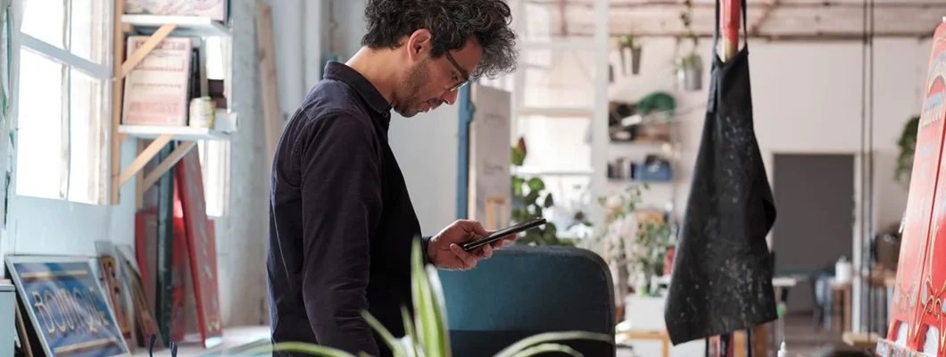 Man standing with a phone in his hand in an art and craft studio. How to Find the Best Business Insurance in Chalco, Nebraska.