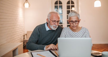 Senior couple researching long term care insurance taxes together. Long term care insurance tax deductions.