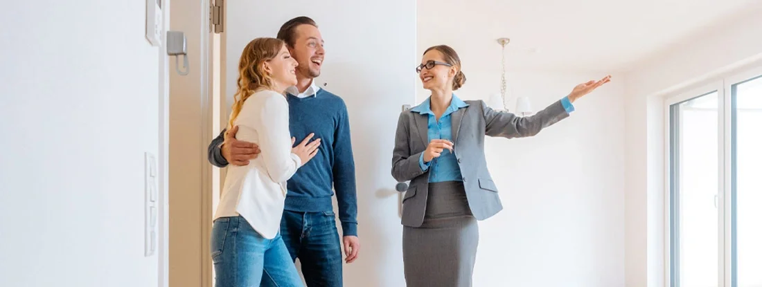 Real Estate Agent showing house to a young couple. Find Iowa Landlord Insurance.