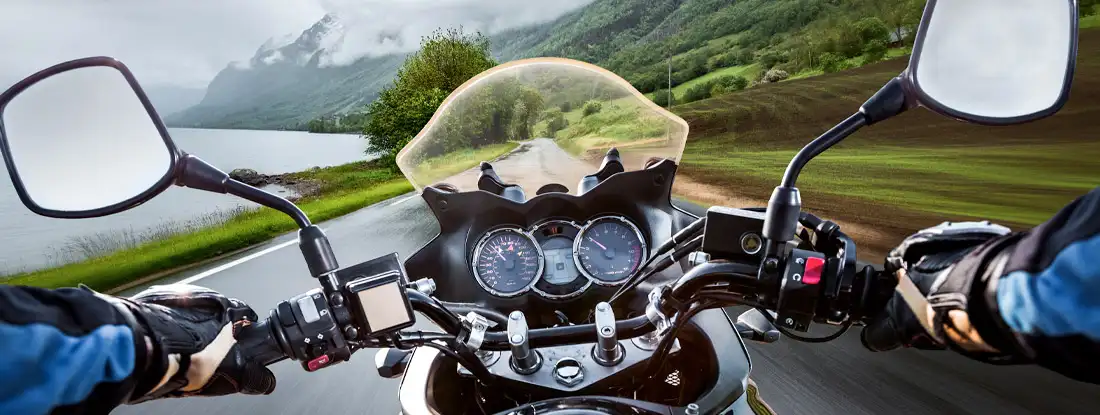 Biker rides a motorcycle in the rain. Find Motorcycle Insurance.