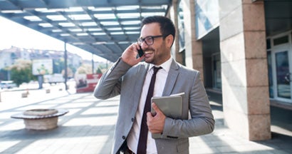 Modern businessman smiling and talking on the phone. Find commercial property insurance.