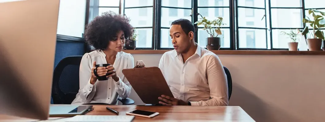 Two young entrepreneurs sitting together at office desk. Find Eagle, Idaho business insurance.