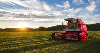 Big red combine harvester in sunset light. How to Insure Farm Equipment.